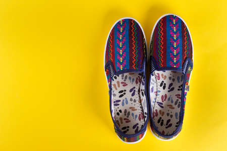 bright multi-colored women's shoes on a yellow background. comfortable trend shoes for summer