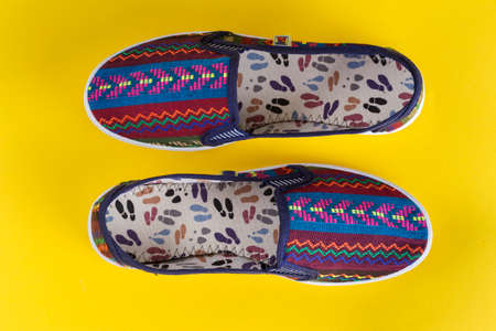 bright multi-colored women's shoes on a yellow background. comfortable trend shoes for summer