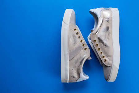 women's new sneakers on a blue background, space for text, top viewの写真素材
