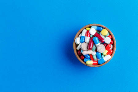 different pills in a plate on a blue background, space for text