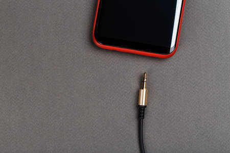 audio cable mini jack and mobile phone on a gray backgroundの写真素材