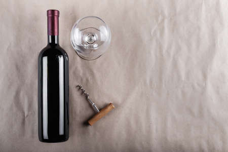 wine set - a closed bottle of red wine with a corkscrew and a glass on a gray backgroundの写真素材