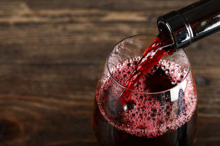in a glass pour red wine, on a wooden background, space for textの写真素材