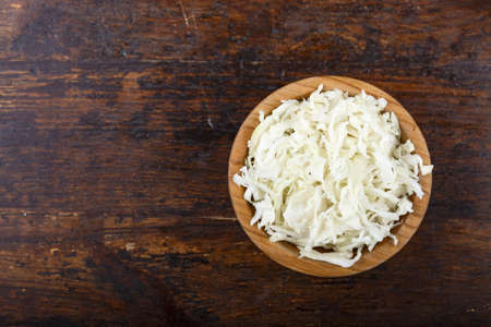 chopped white cabbage in a plate on a wooden background. fresh vegetable saladの写真素材