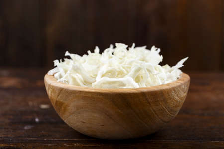 chopped white cabbage in a plate on a wooden background. fresh vegetable saladの写真素材