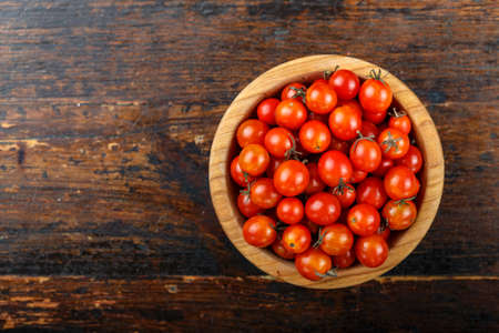 cherry tomatoes on a wooden background in a wooden plate, space for textの写真素材