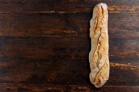 bread baguette with a crisp on a wooden background, traditional European pastries. place for text
