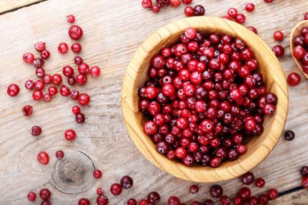Cranberry in a wooden plate on a wooden background. place for textの写真素材