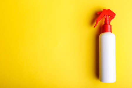 Detergent with spray on a yellow background, space for text