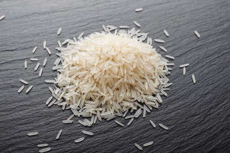 The raw basmati rice is scattered on a black slate. place for textの写真素材
