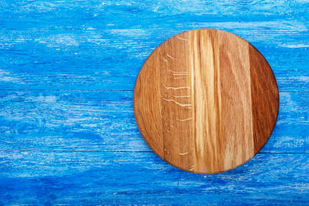 Round pizza board on a wooden surface. view from above. place for textの写真素材