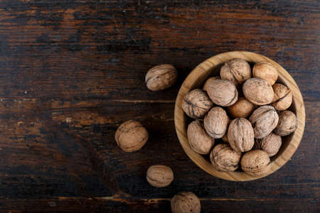 Whole walnuts in a plate on an old country table and against a dark background. place for text