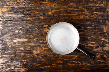 old aluminum frying pan on a wooden background. place for textの写真素材