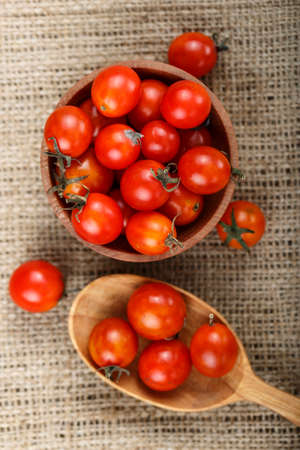 cherry tomatoes on sacking, next to the plate lies a wooden spoon. view from aboveの写真素材