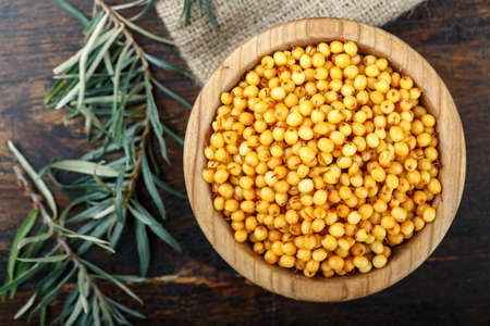 ripe raw sea buckthorn in a plate on a wooden table. place for textの写真素材