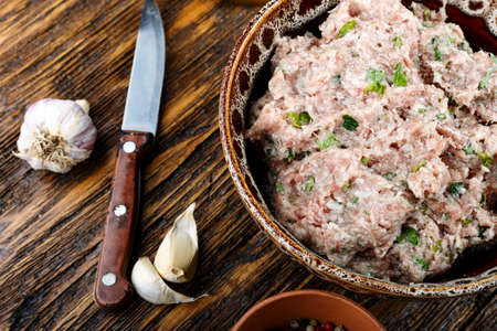 raw minced meat in a plate and spices. on a wooden table, top view
