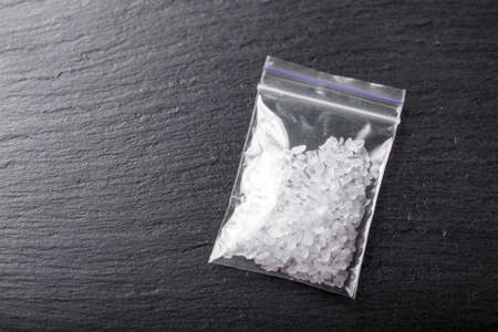 white crystals of a drug in a bag on a black background. place for textの写真素材