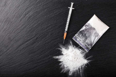 powder drugs and a syringe on a black background. view from above. place for textの写真素材