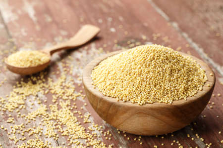 plate with raw cereal millet on a wooden background. preparation of a useful nutritious dish