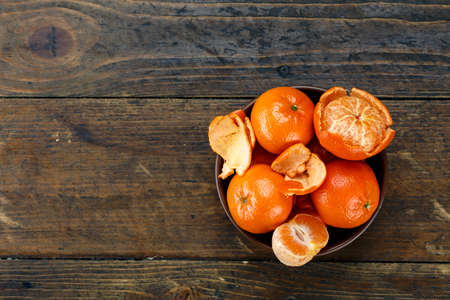 ripe tangerines in the peel and peeled in a plate on a wooden table. space for textの写真素材