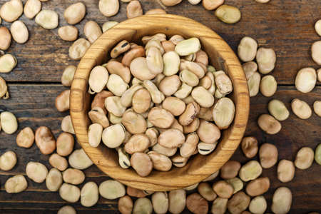 Dried broad beans on a wooden table in a wooden plate. space for textの写真素材