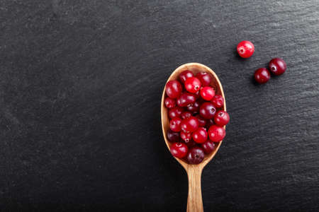 Cranberries on a black background in a wooden spoon. space for textの写真素材