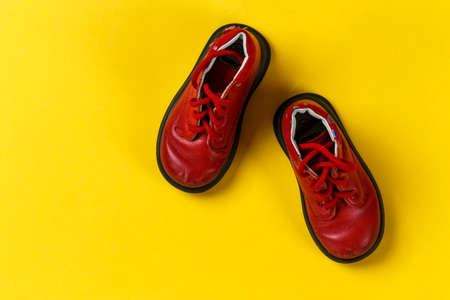 children's autumn red leather shoes on a yellow background. space for textの写真素材
