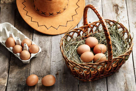 raw chicken eggs in a basket on the table. near the hat and tray. rustic lookの写真素材