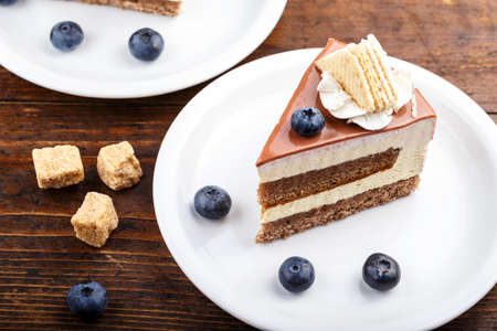 Slice of cheese cake with blueberries on a brown wooden background