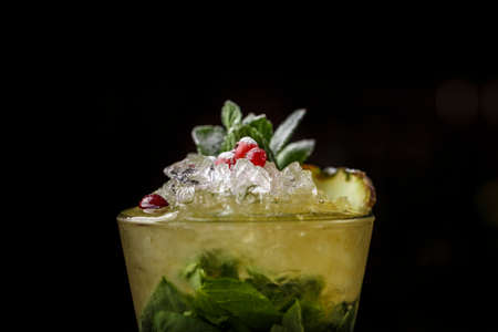 Mojito cocktail in a glass on a dark background. There is mint and cranberry in the glass. New Year's cocktailの写真素材