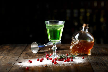 cocktail with absinthe for Halloween in a glass in the form of a skull