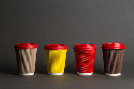 many different types of coffee in paper glasses on a black background, space for textの写真素材