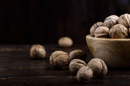 inshell whole walnuts on dark wooden background. in a wooden plateの写真素材