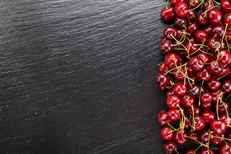 red sweet cherries scattered on a black background. space for textの写真素材