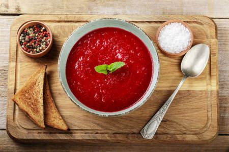 gazpacho tomato soup in a plate on the table. nearby are croutons and spices. space for text