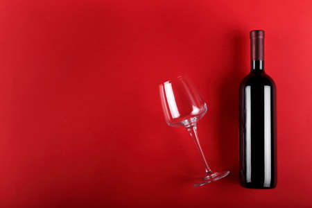 bottle of wine and a glass on a red background. space for textの写真素材
