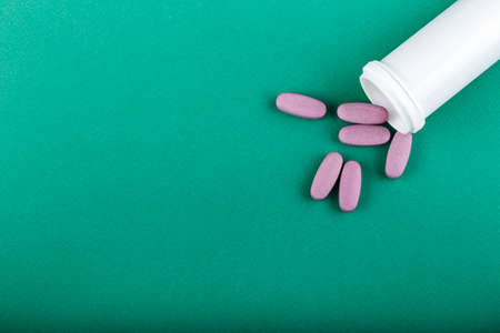 scattered pink pills from the bottle on the table. space for textの写真素材