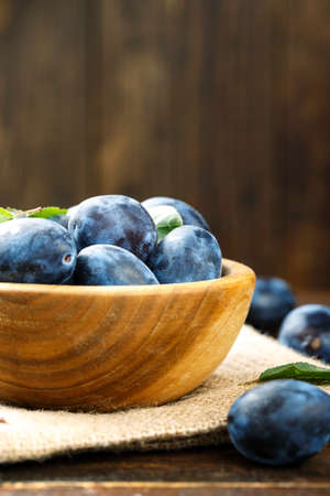 ripe purple organic plums on a wooden background. space for textの写真素材