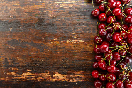sweet red cherries lined up in a row on a brown wooden background. space for textの写真素材