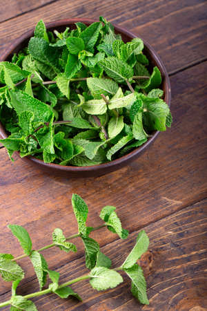 fresh mint in a plate on a brown wooden background