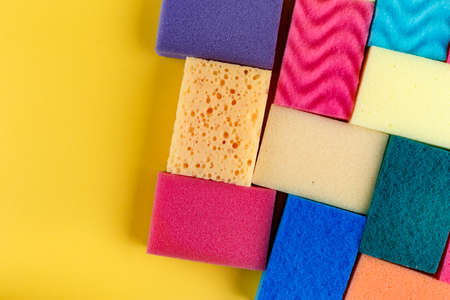 Many multicolored sponge for washing dishes on a yellow background. space for textの写真素材