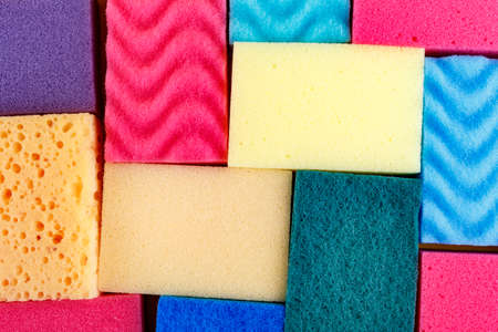 Many multicolored sponge for washing dishes on a yellow background. space for text