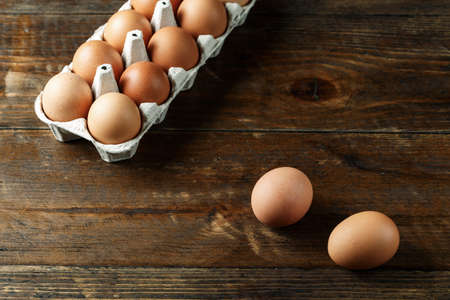 chicken eggs in a paper tray on wooden background. space for text