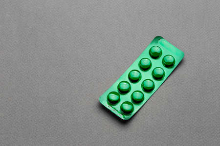 pills in a green blister on a black background. drug treatment of diseases. space for textの写真素材