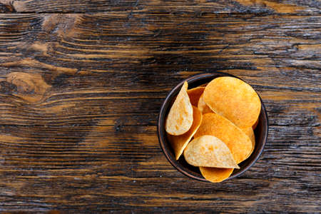 Crispy potato chips in a clay plate on old kitchen tableの写真素材