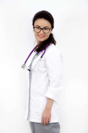 young girl doctor with a stethoscope and in uniform on a white wall backgroundの写真素材