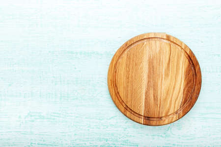 empty round wooden pizza board on light blue wooden background. space for text