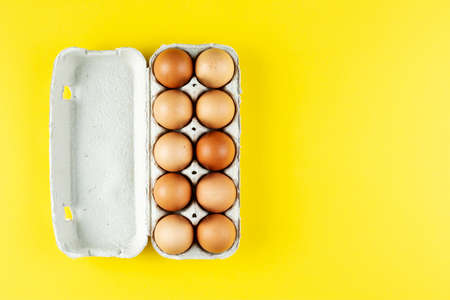 a dozen brown chicken eggs in a cardboard tray on a bright background. space for text