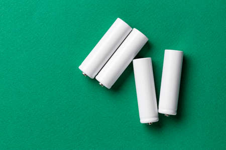 white batteries scattered on a green background. space for textの写真素材