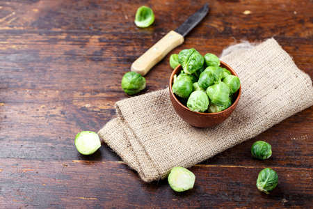 Brussels sprouts in a clay plate on a brown wooden backgroundの写真素材